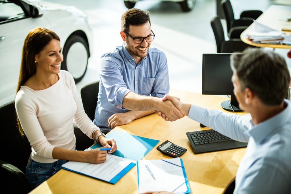 Happy couple buying a car in a showroom