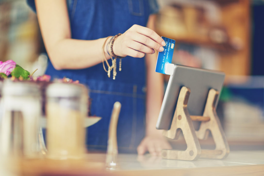 apron of cafe owner who is swiping credit card using digital tablet.