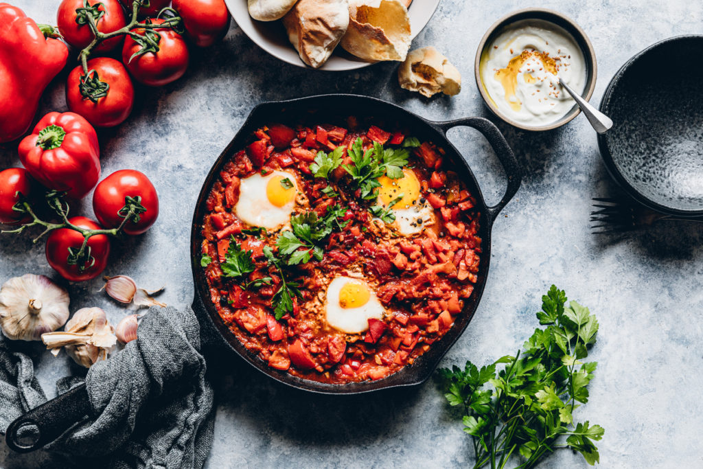 Top view of delicious shakshuka with eggs poached in a spicy sauce of tomatoes and vegetables.