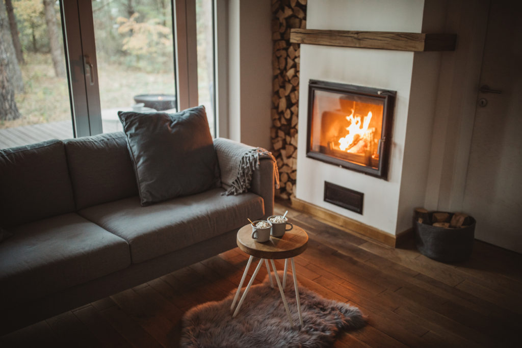 Cozy home interior with fireplace and keeping warm with hot drink