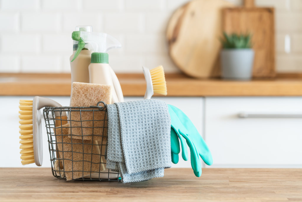 Basket with brushes, rags, natural sponges and cleaning products.